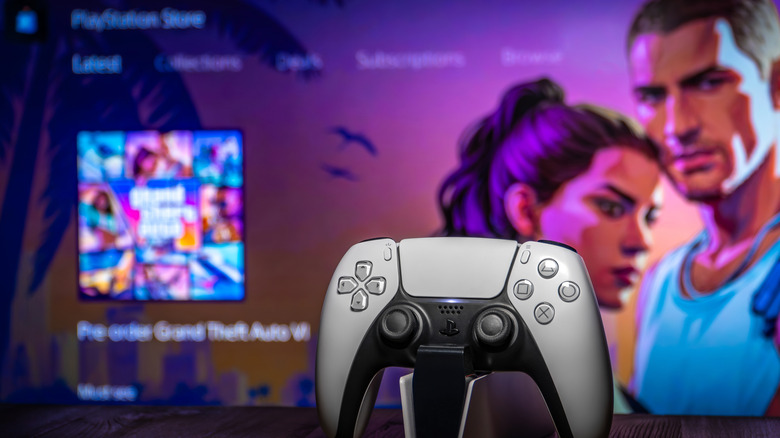 DualSense controller on top of a PlayStation 5 with a TV showing Grand Theft Auto VI in the background