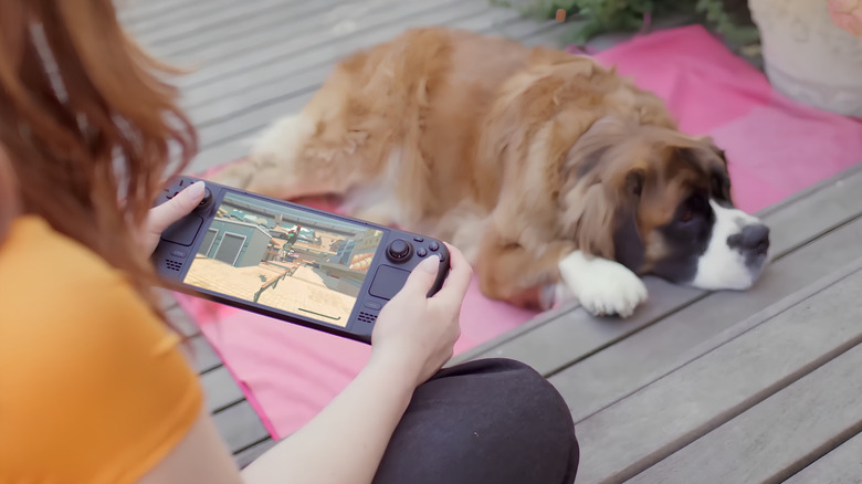 Woman playing a Stream Deck OLED while her Dog relaxes.