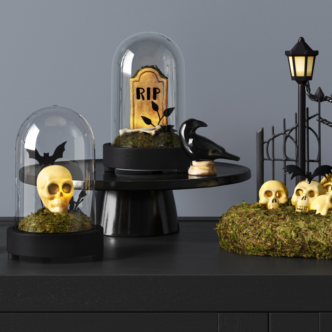 Tabletop decorated with a skull under a glass cloche, a raven figurine, moss-covered skulls, a tombstone display and black metal lantern decor.