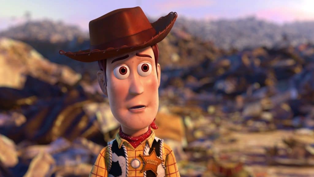 The image shows Woody from Toy Story 3 standing in a landfill.