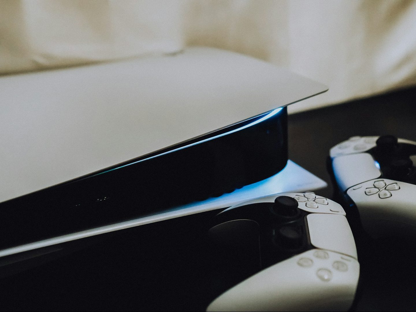 A PS5 sitting on its side with two Dualsense controllers next to it on the right.