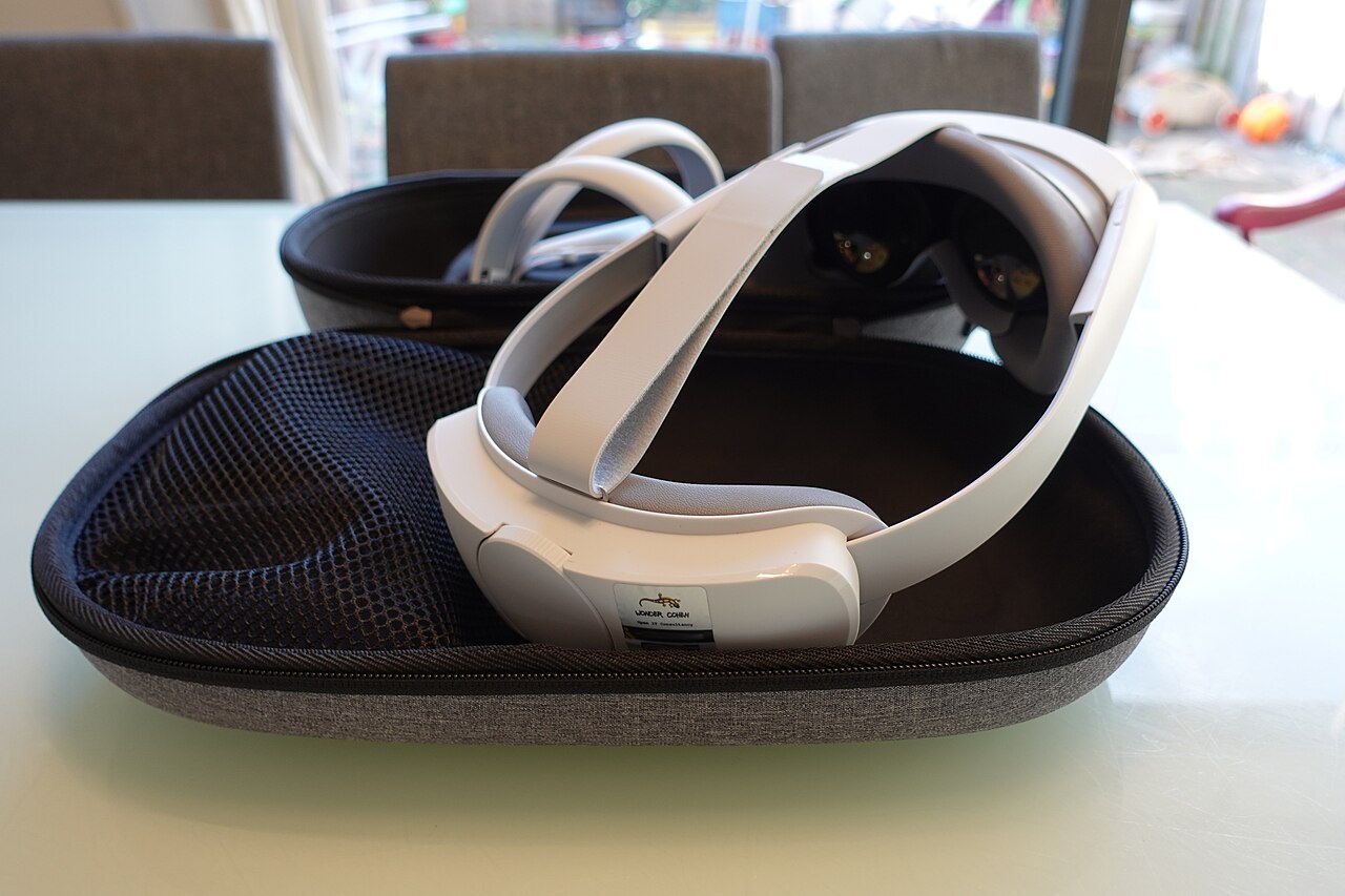 A white Pico 4 headset resting in an open grey carrying case on a table, seen from behind with the halo strap and rear pad facing the camera
