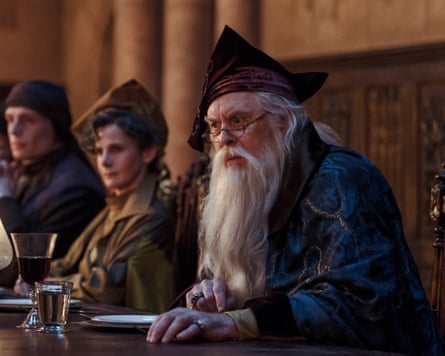 Man with long white beard and hat sits at table with other people