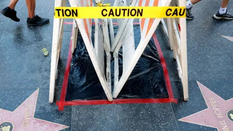 Getty Images Dolly Parton's star on the Hollywood Walk of Fame on Hollywood Boulevard in Hollywood, covered with black plastic, white barriers and yellow "caution" tape