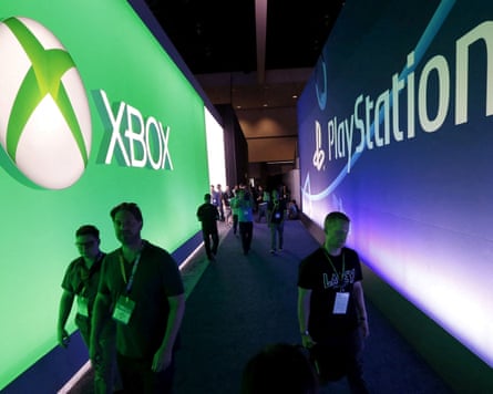 Attendees walk past a Microsoft Xbox sign opposite a Sony PlayStation sign.