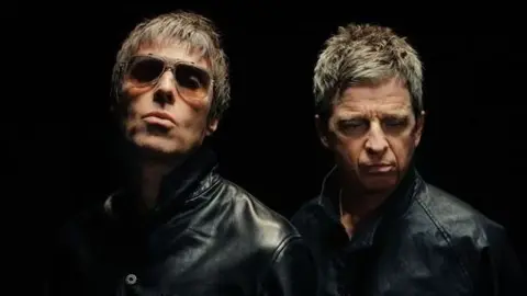 Joshua Halling Liam and Noel Gallagher, both wearing black and looking serious in front of a black backdrop. Liam is wearing sunglasses
