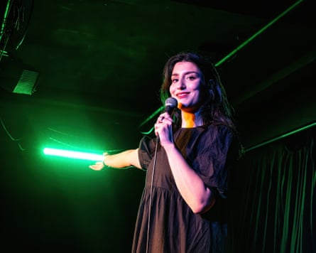 Celya AB on stage gesturing toward a neon light