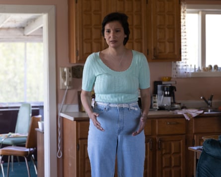 A woman stands in a kitchen looking distressed.