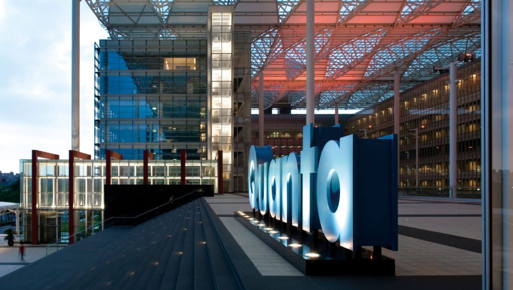 Quanta Computer campus at dusk, with the word quanta spelled out in illuminated freestanding letters in front of a glass and steel building under a red-lit canopy