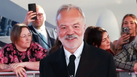 Getty Images Graham Norton smiles as he stands on the National Television Awards red carpet