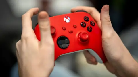 Getty A close up of someone's hands holding a red Xbox controller