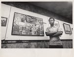 Young cartoonist Rupert Kinnard poses next to a display of his original comic characters.