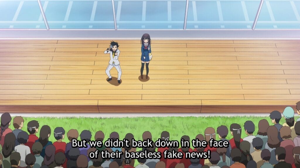 Far shot showing Pontaro on stage with Yoka. He is gesturing wildly and yelling into a microphone. Subtitle text reads: But we didn't back down in the face of their baseless fake news!