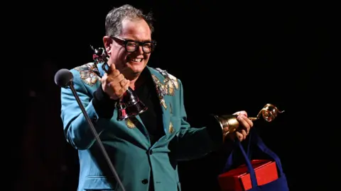 Getty Images Alan Carr accepts the 'Special Recognition' award on stage during the National Television Awards 2026 show at The O2 Arena.