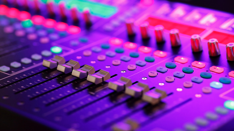 An audio mixing desk cast in purple light.