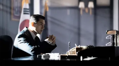 Baek Ki-tae (Hyun Bin) sitting at a desk, resting his elbows on it.