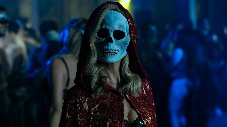 A woman in a skeleton masks stares at someone eerily.