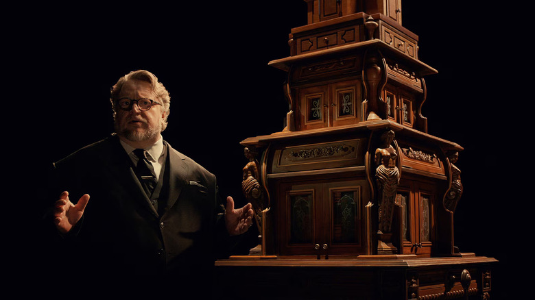 Guillermo del Toro stands next to a model of a tower