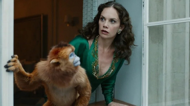 Marisa Coulter looking out window with orange monkey next to her