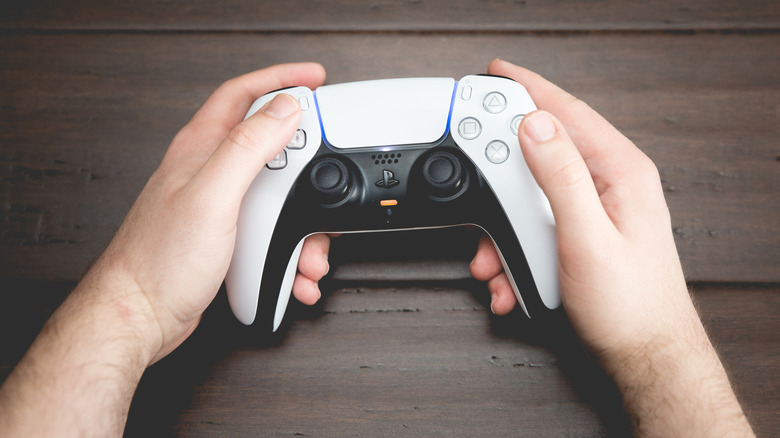 A closeup of a man holding a DualSense controller.