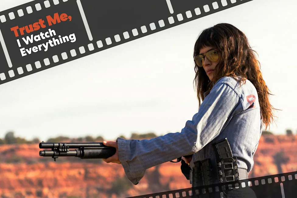 Adria Arjona in "Onslaught." Woman in tinted glasses holds a shotgun outdoors beneath filmstrip graphics reading "Trust Me, I Watch Everything.