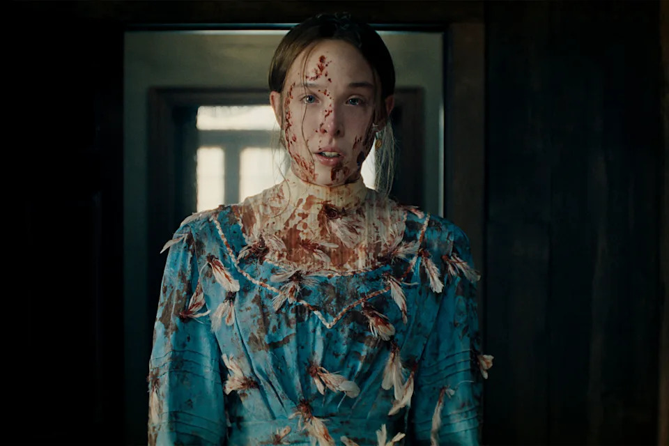 Ella Beatty wearing a blue dressed covered in fake blood and feathers
