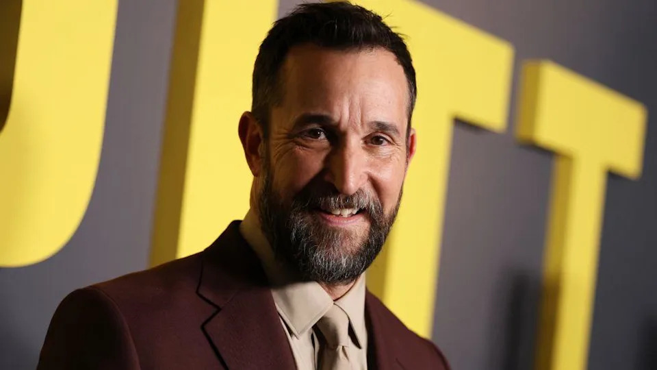 Noah Wyle at The Pitt Los Angeles premiere, wearing a brown suit and beige shirt and tie