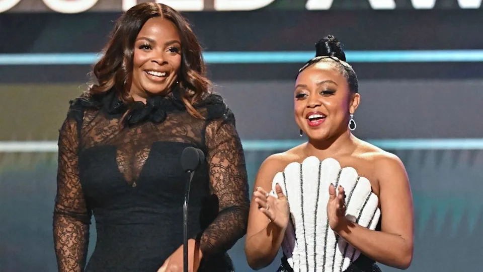 Janelle James and Quinta Brunson speak onstage at the 29th Actors Guild Awards in LA in February - James is wearing a black lace dress, Brunson is wearing a white corset top