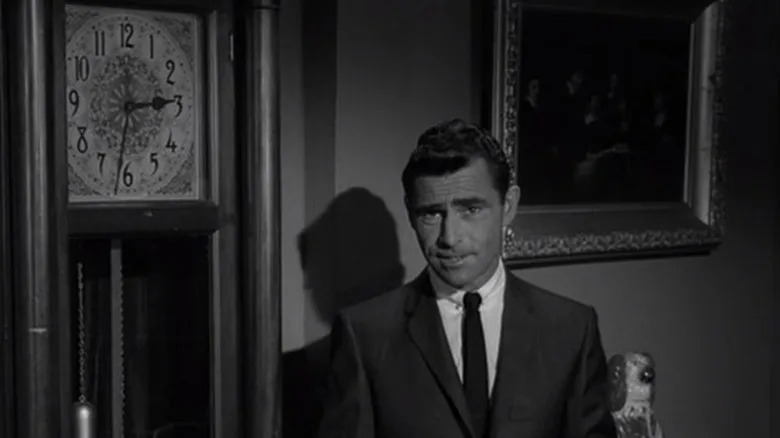 Rod Serling standing in a next to a clock on "The Twilight Zone."