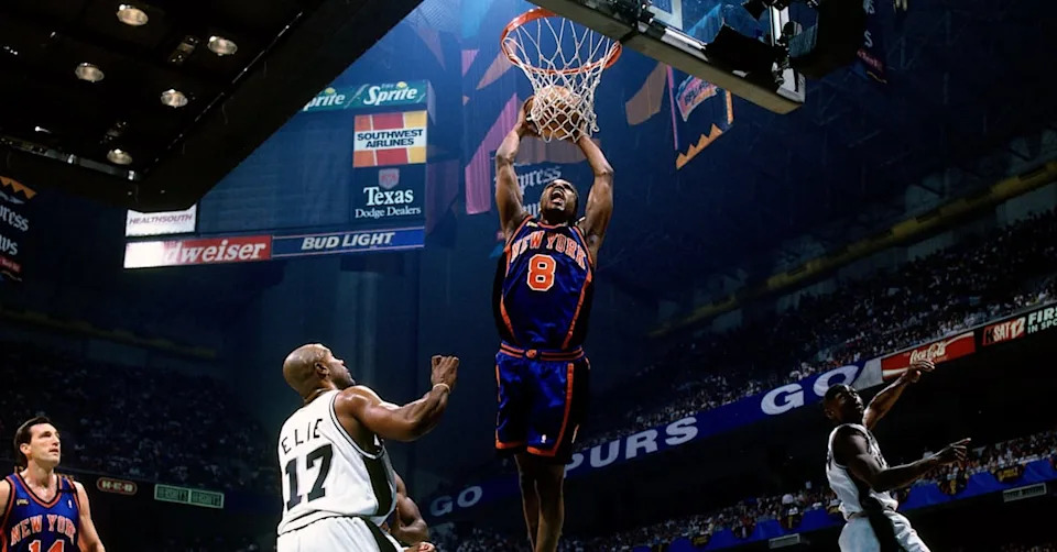 Basketball game scene with a player from the New York Knicks dunking, surrounded by San Antonio Spurs players in an arena.