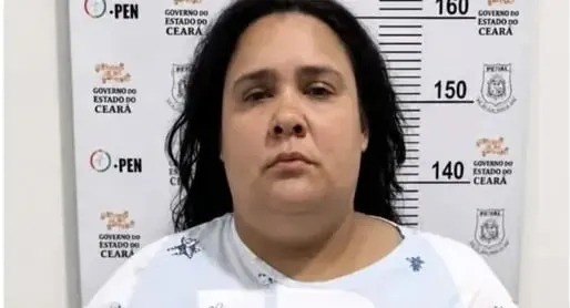 A person holding a sign with identification details, standing against a height chart backdrop.