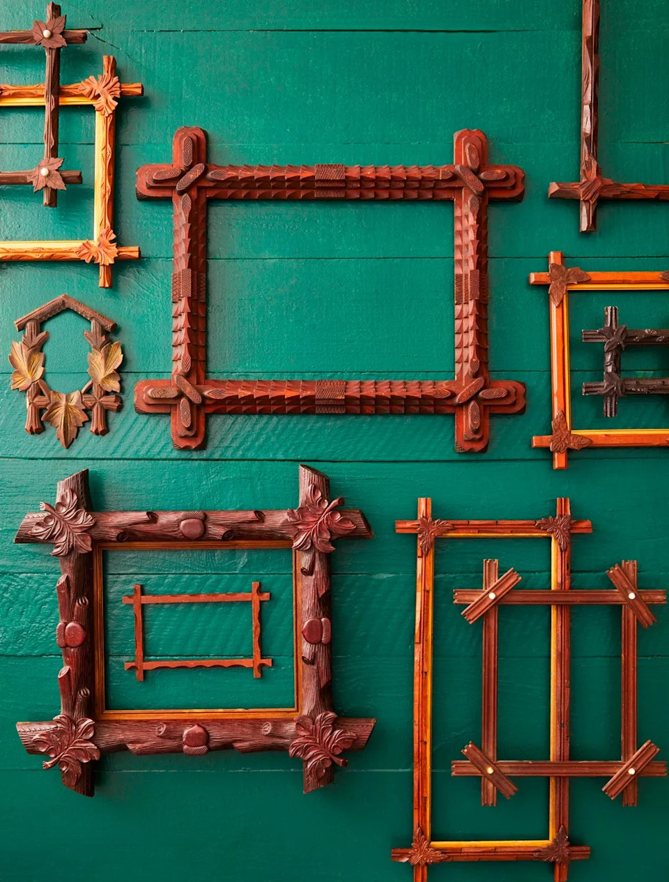 Ornately carved wooden picture frames displayed against a green wooden background.