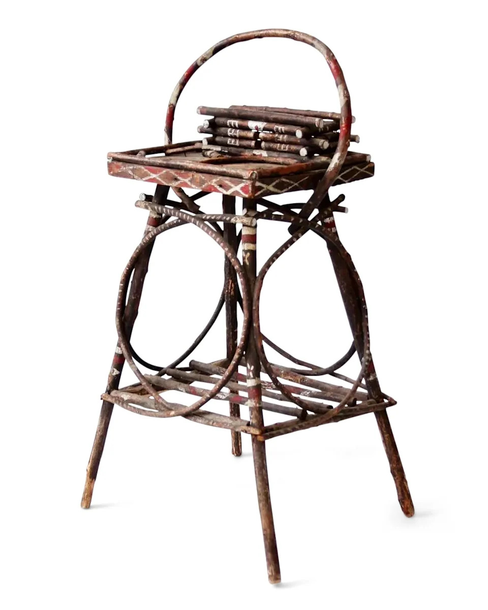 Decorative wooden stool with a circular handle and intricate painted patterns.