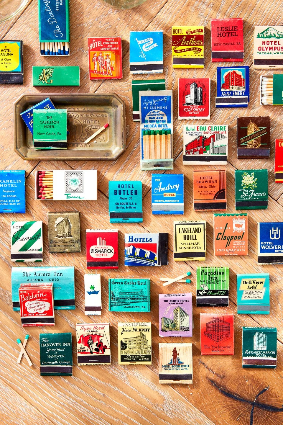 A collection of matchbooks from various hotels displayed on a wooden surface.