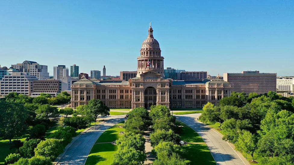 The Texas State Capitol stands on Congress Avenue with the downtown skyline in Austin. Photo: Mitchell Kmetz / Unsplash