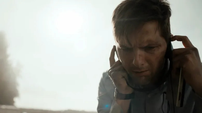 Justin Sanderson holding his fingers in his ears as he tries to hear something while standing on a beach in The Twilight Zone (2019)