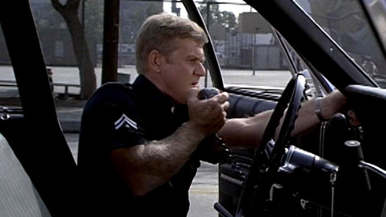 Officer Pete Malloy speaking into his police car radio with the door open in Adam-12