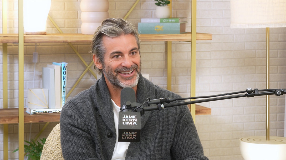 Jim Curtis smiles while seated in front of a podcast microphone.