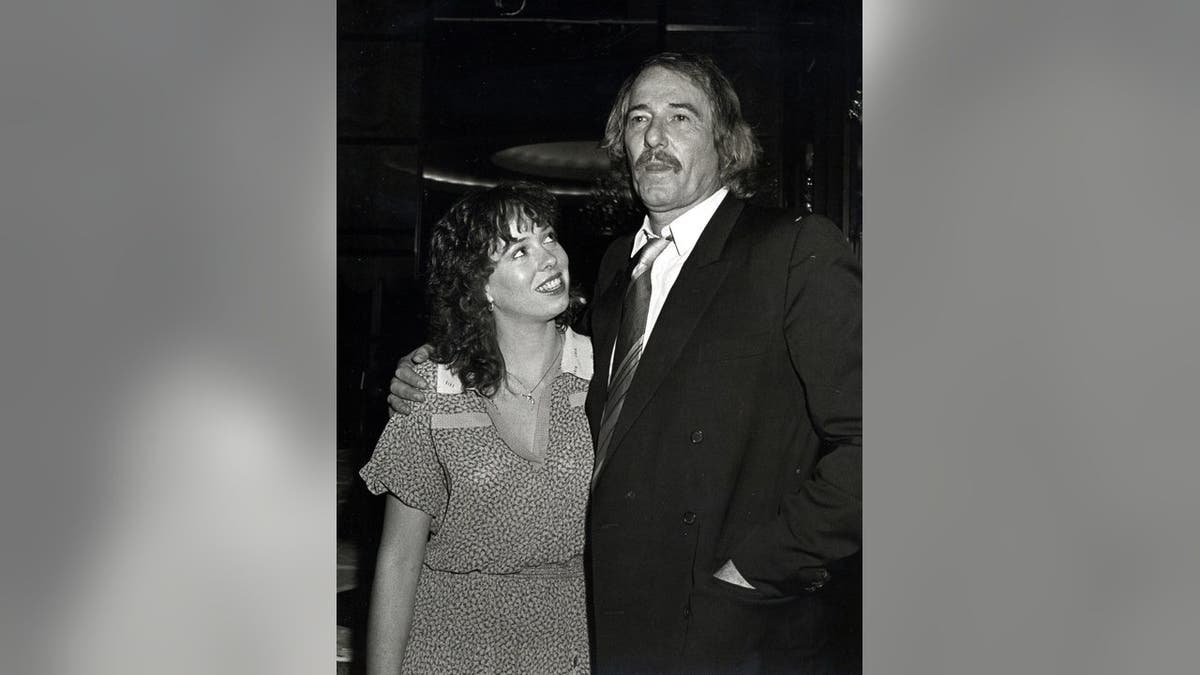 Mackenzie Phillips and John Phillips stand together at a party.