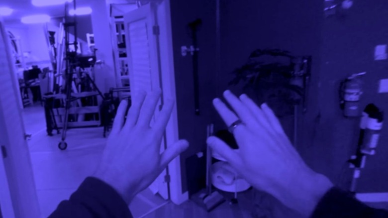 POV shot of a man holding his hands out and navigating an indoors environment through the Steam Frame's monochromatic passthrough vision