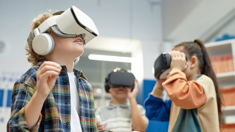 Three children playing with VR headsets on