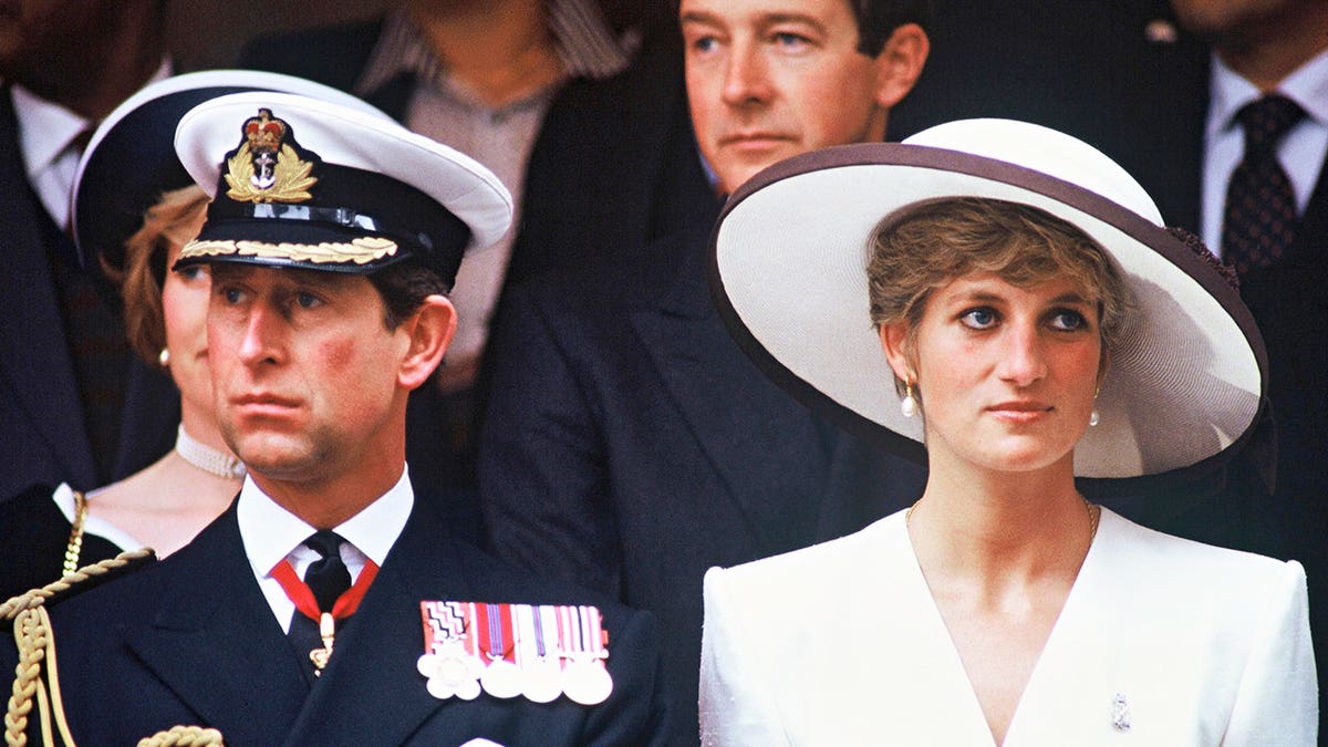 King Charles in uniform and Princess Diana standing together shoulder to shoulder appearing serious in public.