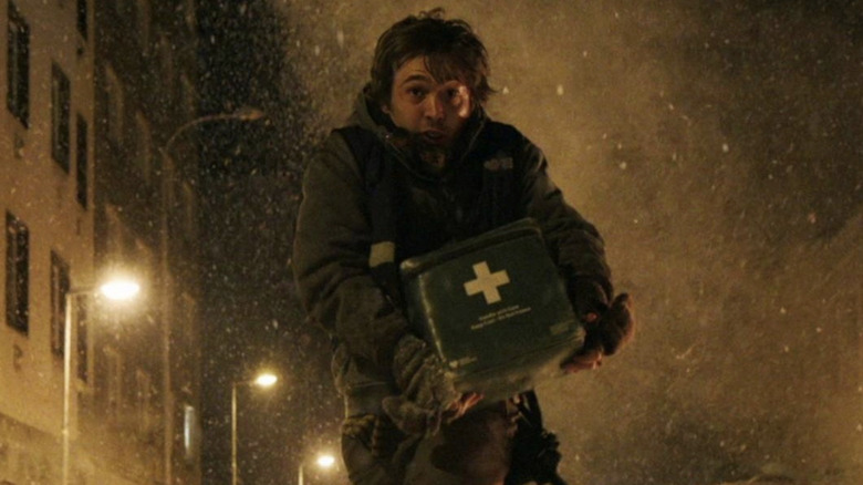 Austin Abrams as Bryan running from falling bodies in a snowy street in Resident Evil