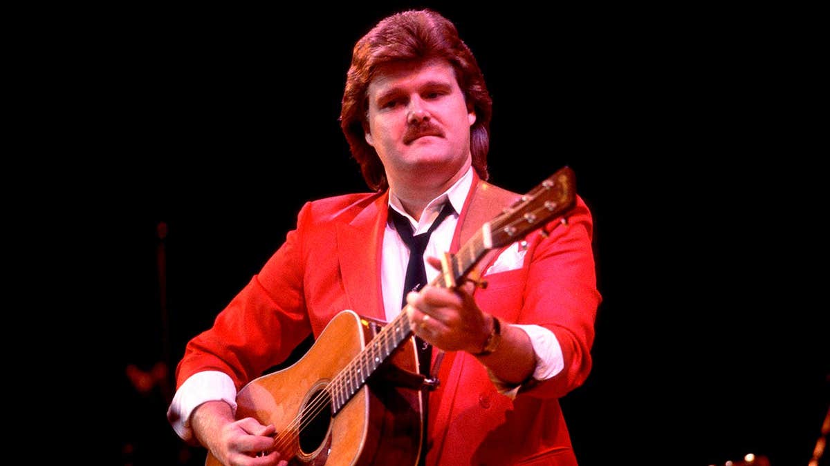 Ricky Skaggs plays guitar while performing onstage.