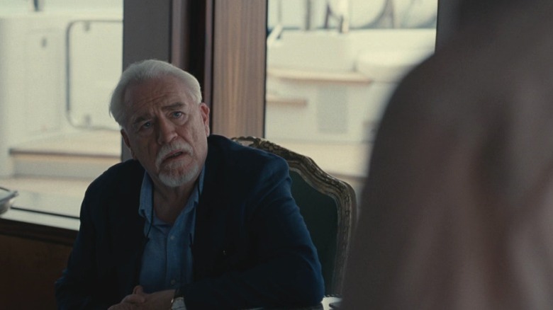 Logan sitting in a chair and looking up at Kendall on Succession S2E10