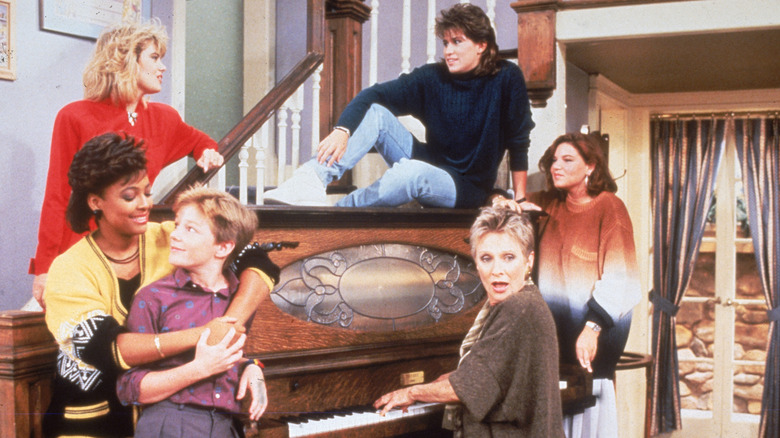 The Facts of Life cast pose around a piano