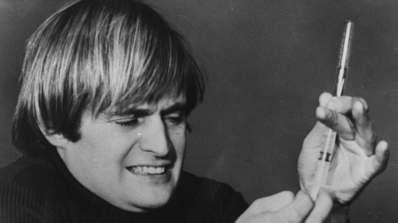 The Invisible Man experiments with a syringe.