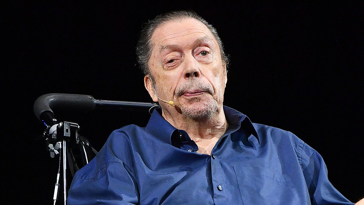 Tim Curry hablando ante el público, sentado en una silla de ruedas