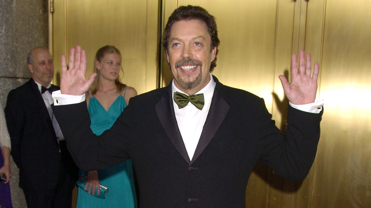 Tim Curry posa con las manos en alto a la salida de los Premios Tony en 2005.