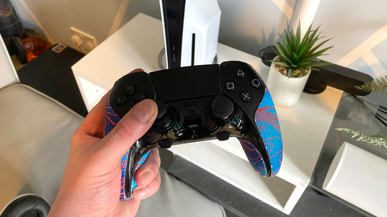 A DualSense Edge Controller with a PS5 Pro console in the background.